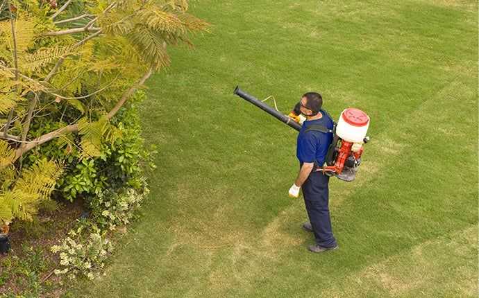 Allstate technician wearing the dark blue uniform polo shirt and mechanic style pants treating a yard for mosquito control